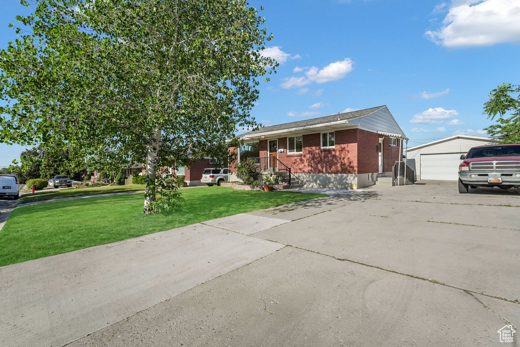 Ranch-style house featuring an outdoor structure, a garage, brick siding, and a front yard