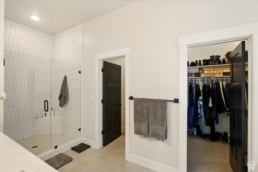 Bathroom with a shower stall, tile patterned floors, a walk in closet, and baseboards