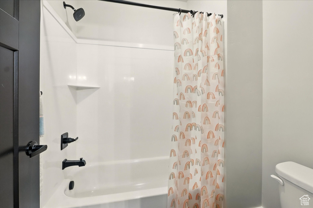 Full bathroom featuring shower / bathtub combination with curtain and toilet