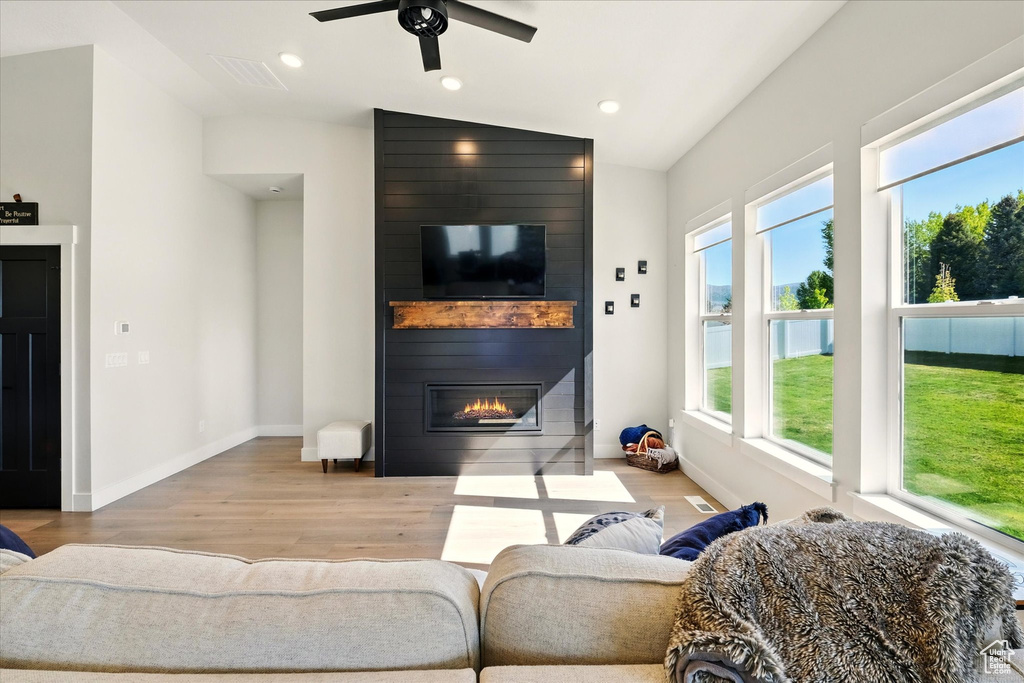 Living area with wood finished floors, a large fireplace, ceiling fan, vaulted ceiling, and baseboards