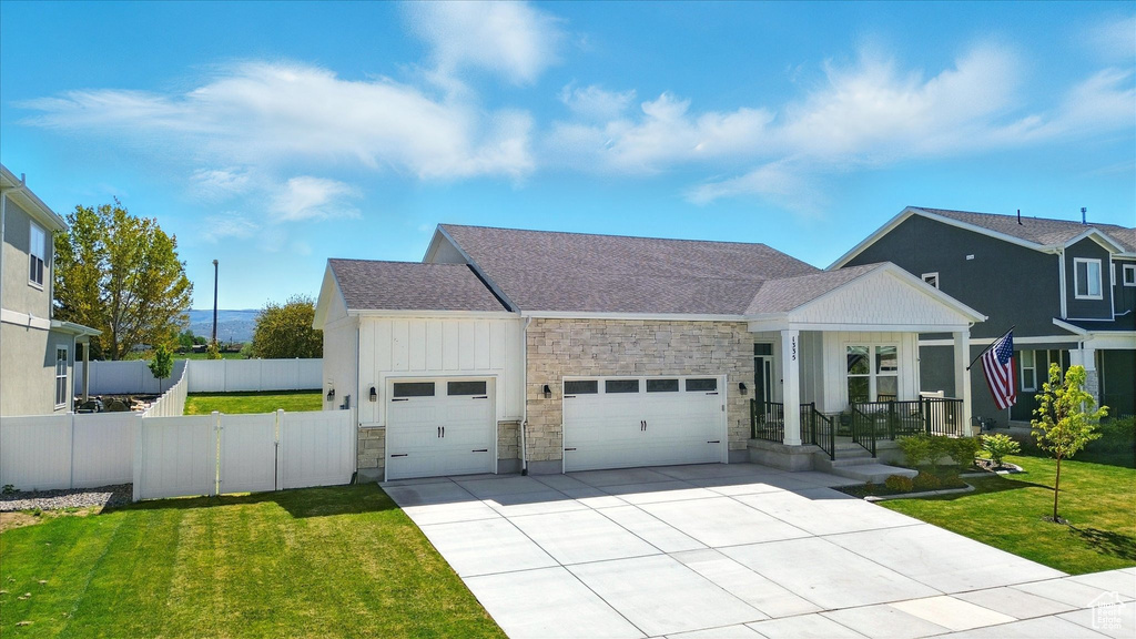 View of front of house featuring a garage, stone siding, board and batten siding, roof with shingles, and concrete driveway