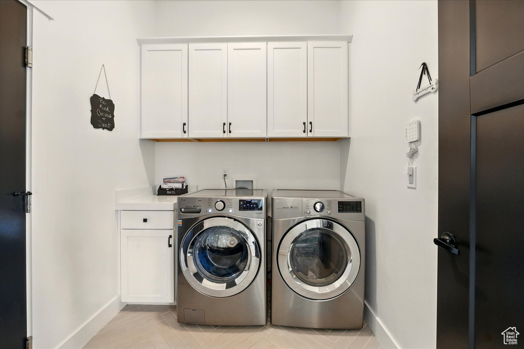 Washroom with cabinet space, washer and dryer, and baseboards