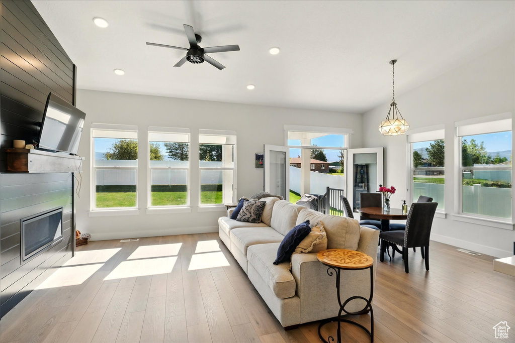 Living room with a fireplace with flush hearth, plenty of natural light, wood-type flooring, and recessed lighting