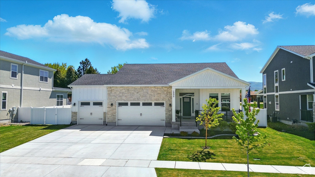 View of front of house featuring board and batten siding, an attached garage, stone siding, concrete driveway, and covered porch