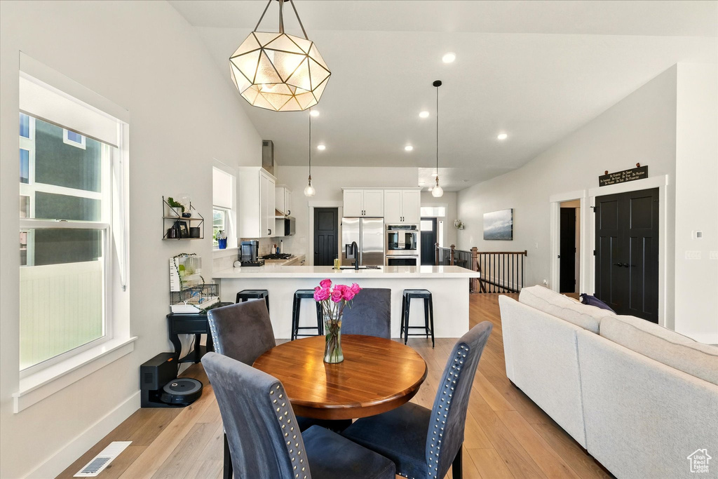 Dining space featuring light wood-style flooring, plenty of natural light, recessed lighting, baseboards, and vaulted ceiling