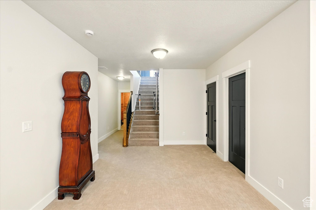 Empty room with baseboards, stairway, and light carpet