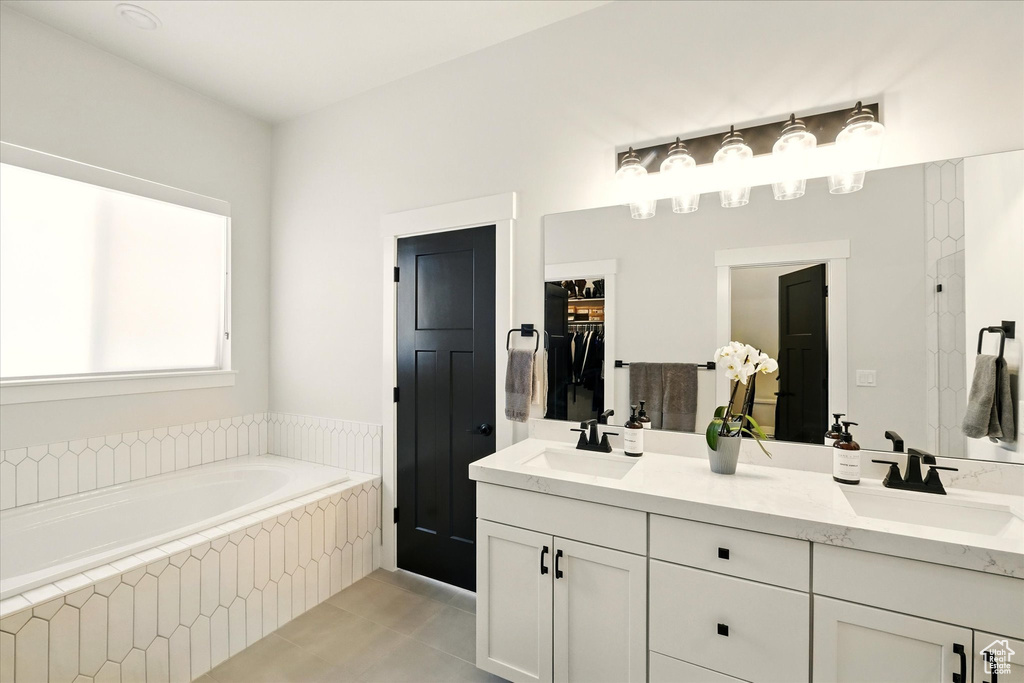 Bathroom with double vanity, a bath, tile patterned floors, and a closet