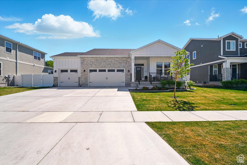 View of front of home featuring a garage, stone siding, concrete driveway, and a porch
