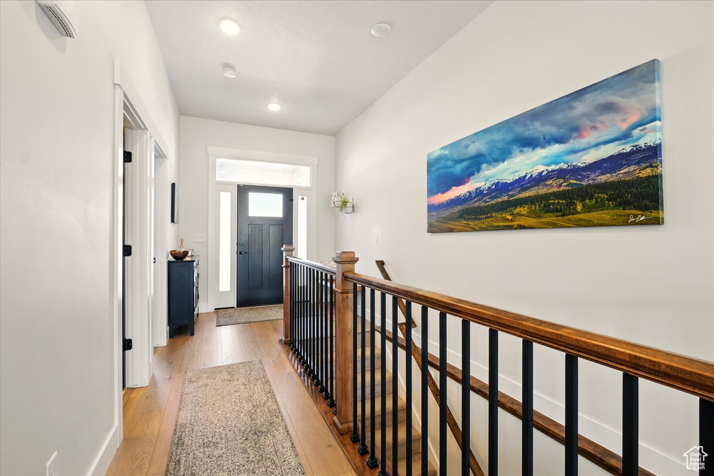 Hallway featuring light wood finished floors, an upstairs landing, recessed lighting, and baseboards