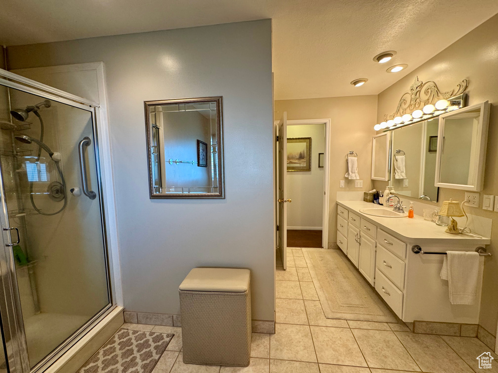 Bathroom with double vanity, tile patterned floors, a stall shower, and baseboards