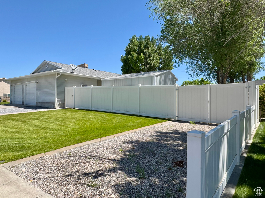 View of side of property with an attached garage, a gate, and driveway