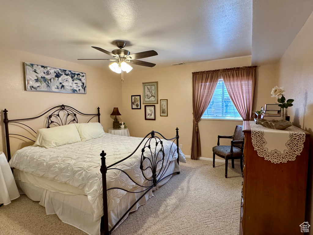 Bedroom featuring light colored carpet, ceiling fan, and baseboards