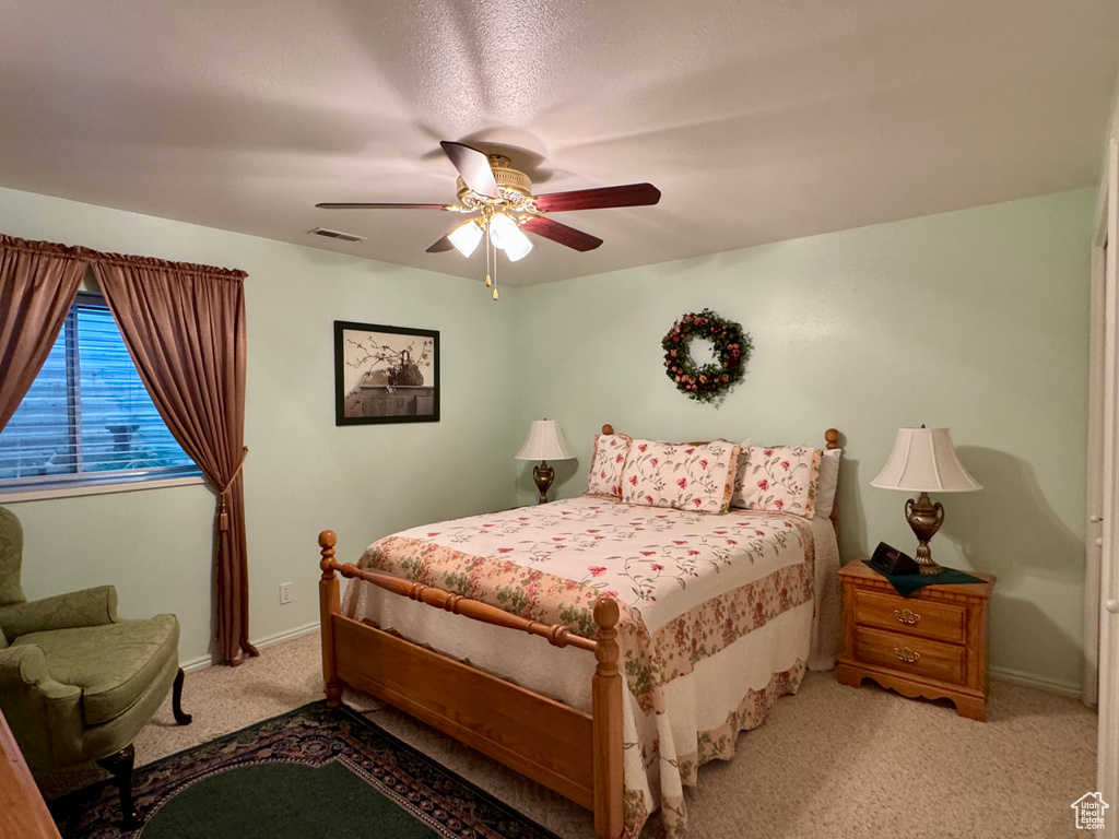 Bedroom with light colored carpet, baseboards, and ceiling fan