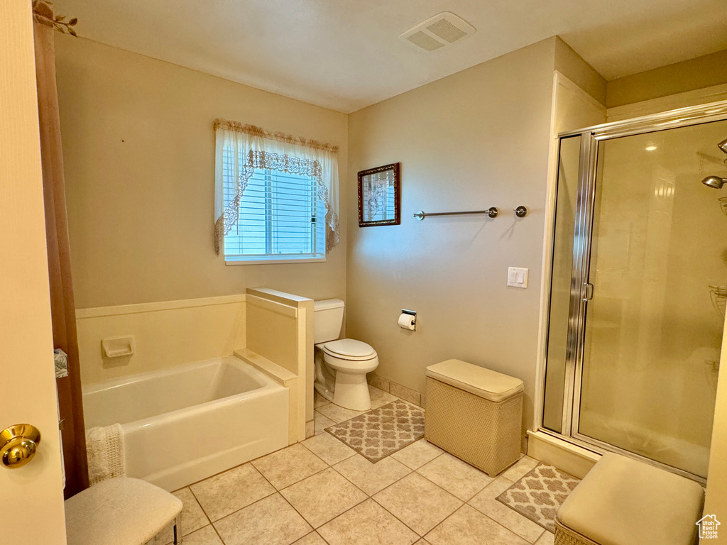 Bathroom featuring tile patterned floors, toilet, a garden tub, and a stall shower