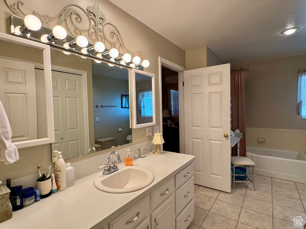 Bathroom with toilet, tile patterned flooring, a bathtub, and vanity