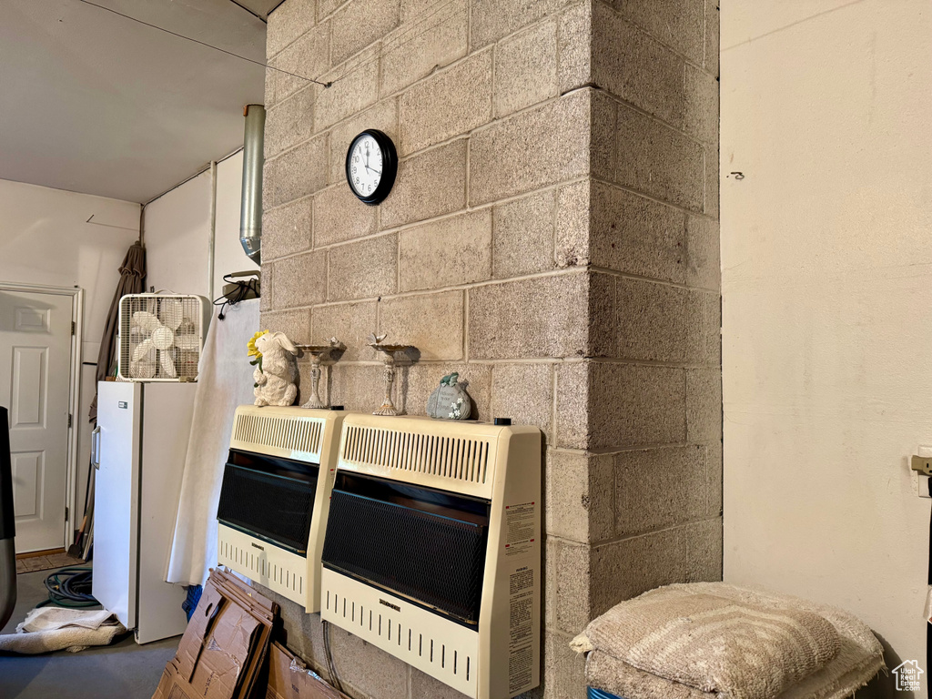 Detailed view of heating unit, concrete block wall, and freestanding refrigerator