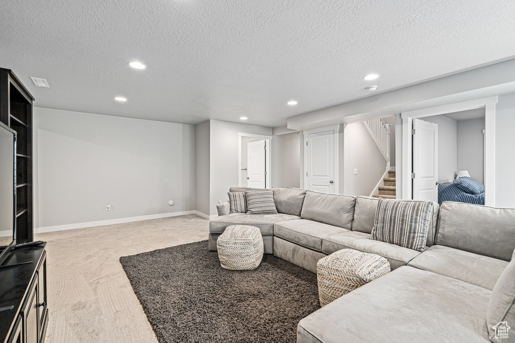 Living room featuring recessed lighting, carpet floors, stairs, a textured ceiling, and baseboards
