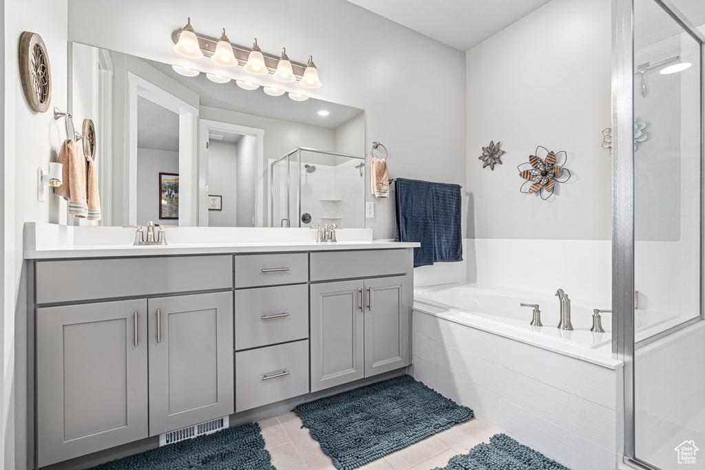 Full bath with a stall shower, double vanity, a bath, and tile patterned floors