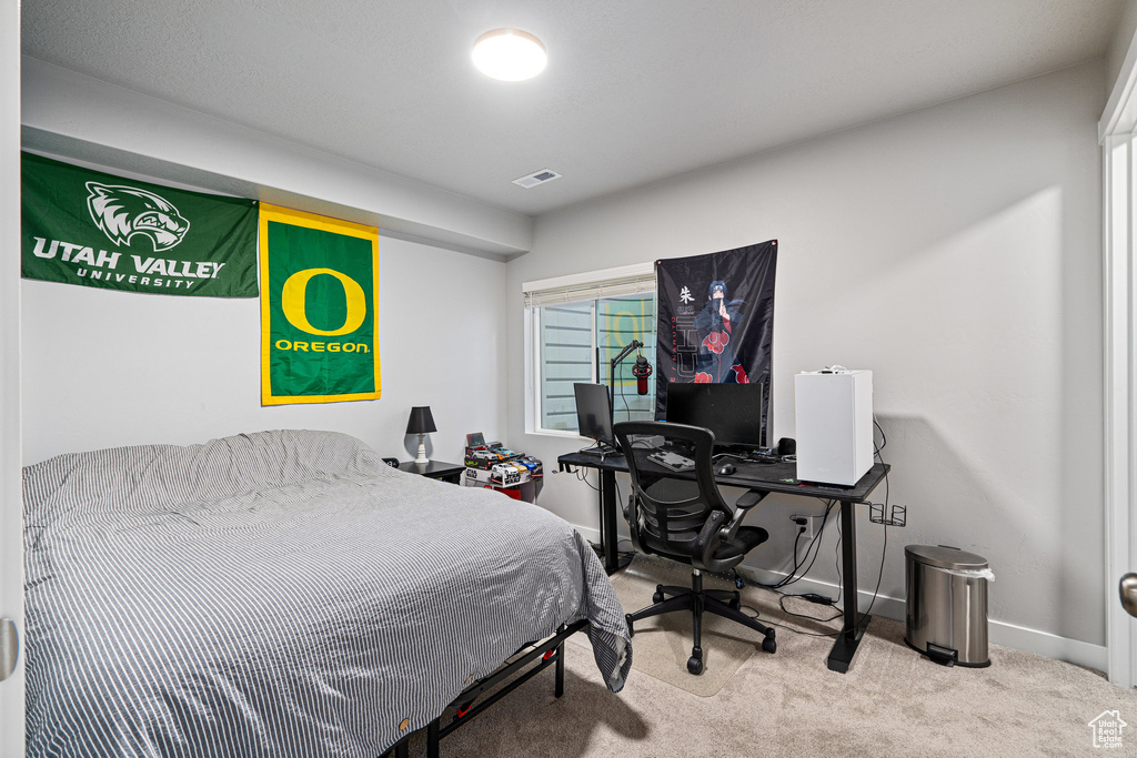 Carpeted bedroom featuring baseboards and an office area