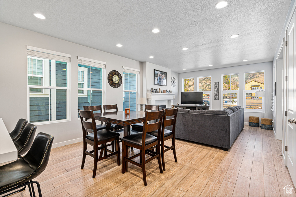Dining space featuring a textured ceiling, light wood finished floors, baseboards, and recessed lighting