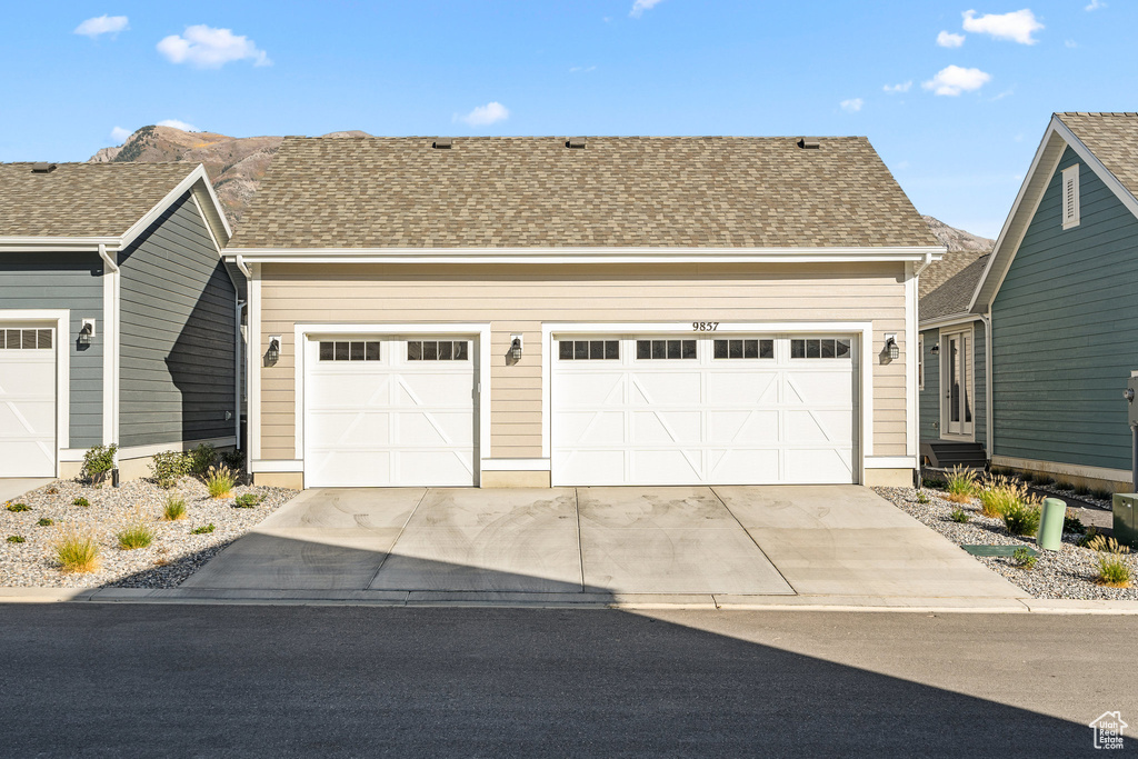 View of front facade featuring concrete driveway, an attached garage, and roof with shingles