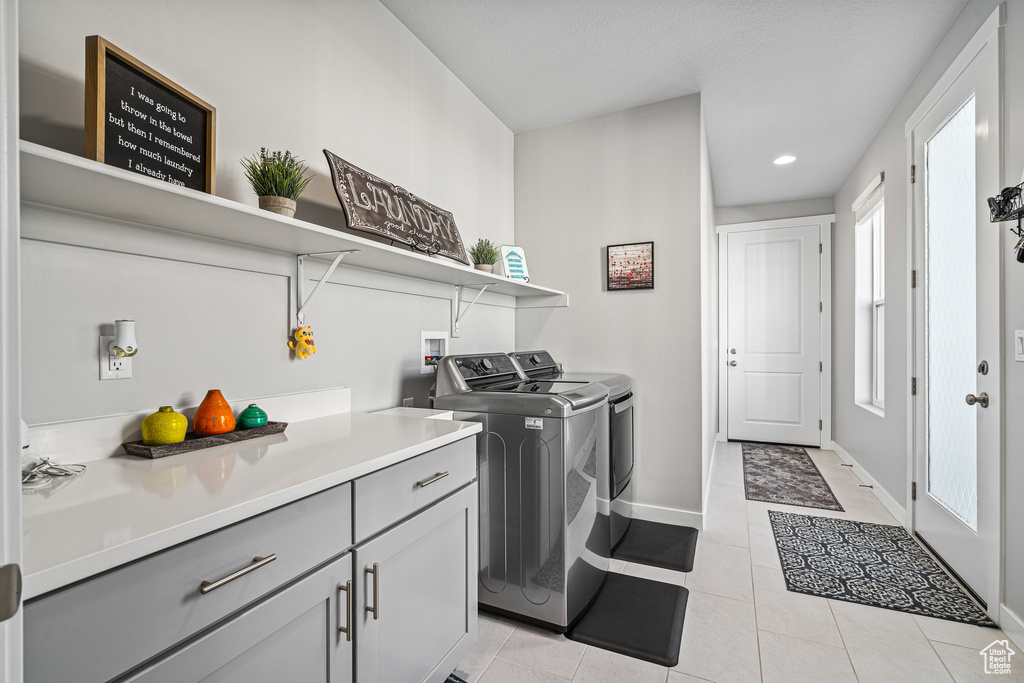 Washroom with washing machine and dryer, recessed lighting, baseboards, light tile patterned flooring, and cabinet space