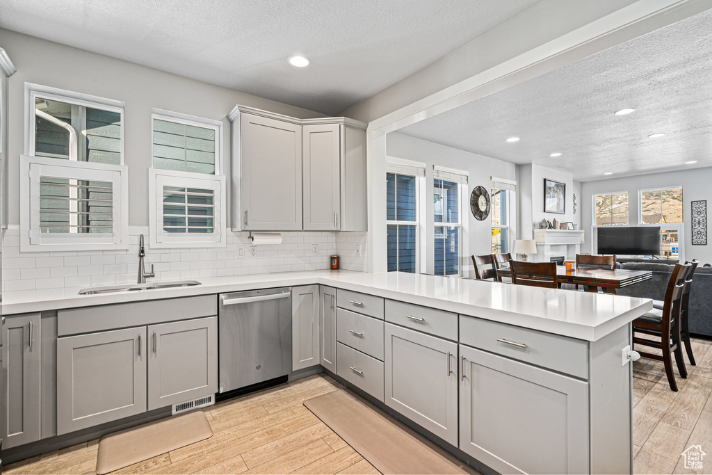 Kitchen with dishwasher, a sink, gray cabinetry, a peninsula, and recessed lighting