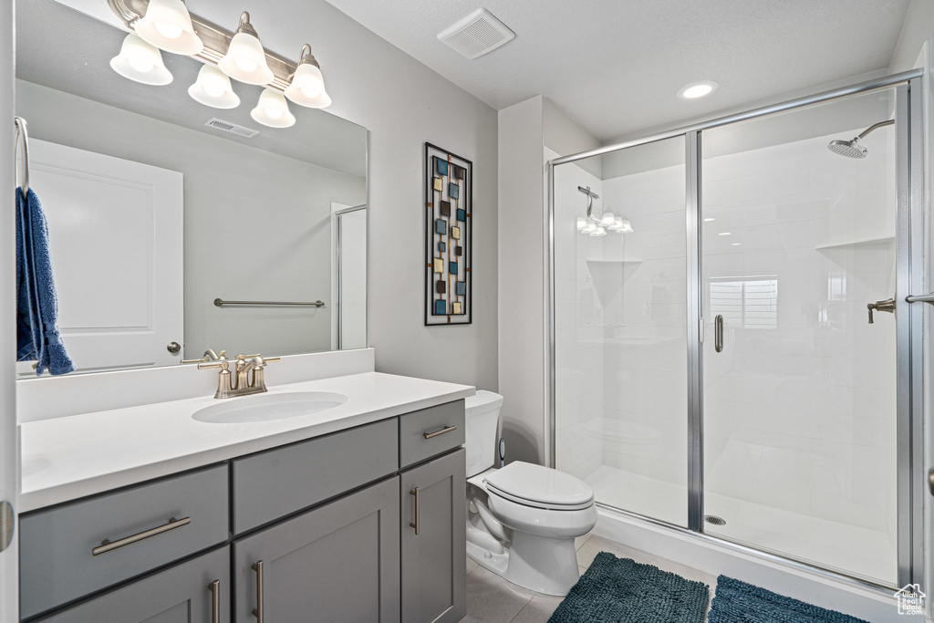 Full bath featuring toilet, vanity, a shower stall, and tile patterned floors