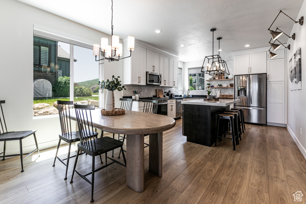 Dining room with a chandelier, dark wood-type flooring, and recessed lighting