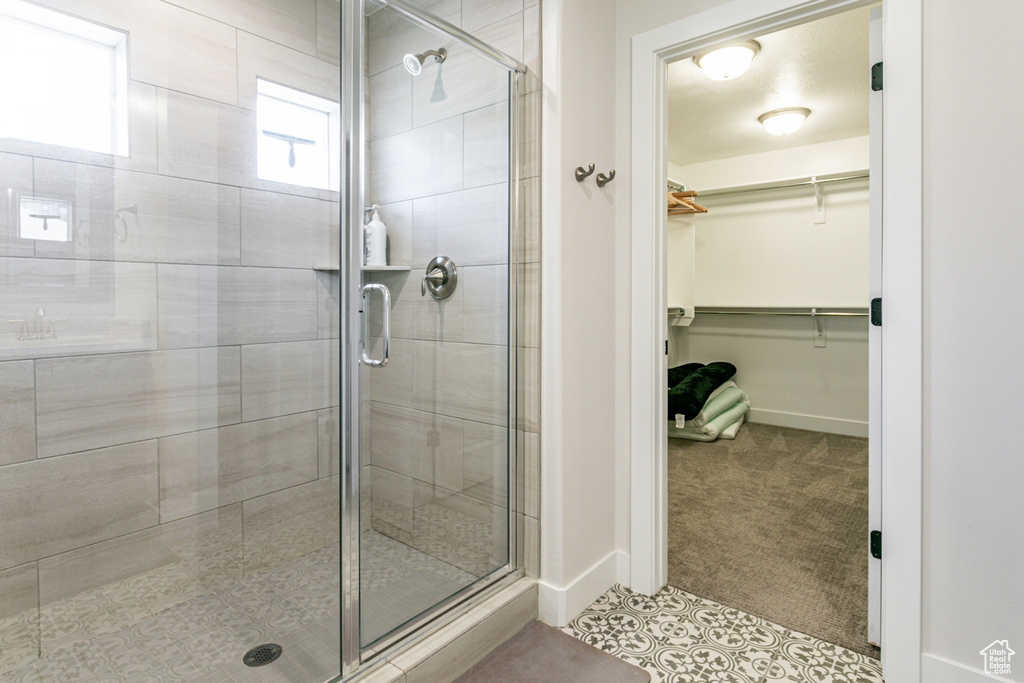 Full bathroom featuring a stall shower, a walk in closet, and tile patterned floors