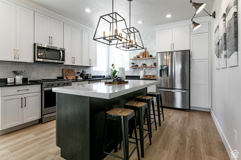 Kitchen with stainless steel appliances, tasteful backsplash, light wood-style flooring, recessed lighting, and a center island