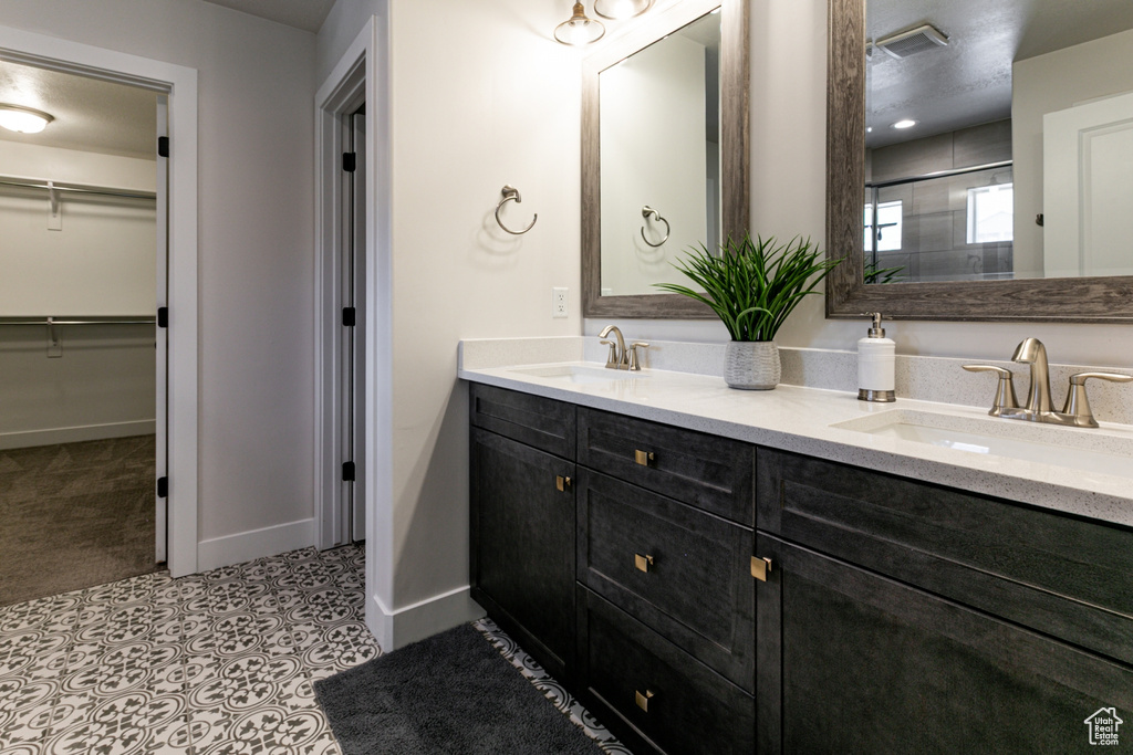 Full bathroom with double vanity, a shower, and a spacious closet