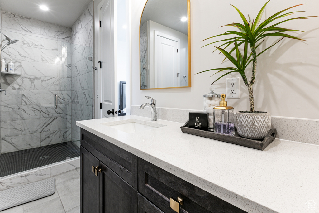 Bathroom with a marble finish shower, vanity, and recessed lighting