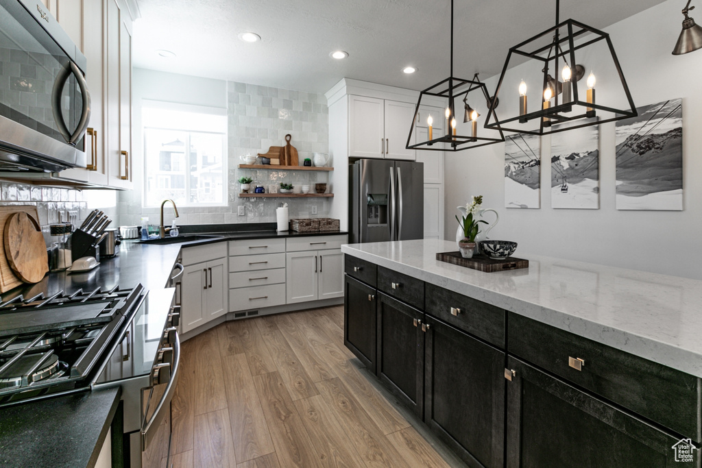 Kitchen featuring appliances with stainless steel finishes, light wood-type flooring, tasteful backsplash, recessed lighting, and dark cabinets