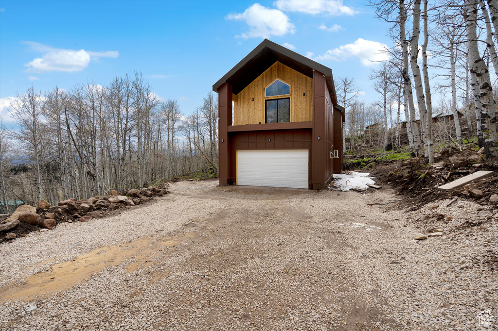 View of front of home featuring dirt driveway and a garage