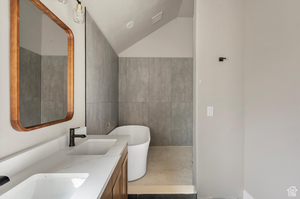 Bathroom with a freestanding bath, double vanity, and lofted ceiling