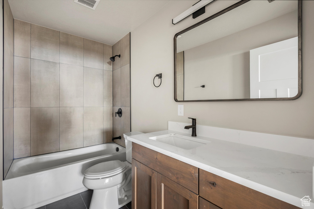 Bathroom featuring toilet, vanity, bathtub / shower combination, and tile patterned flooring