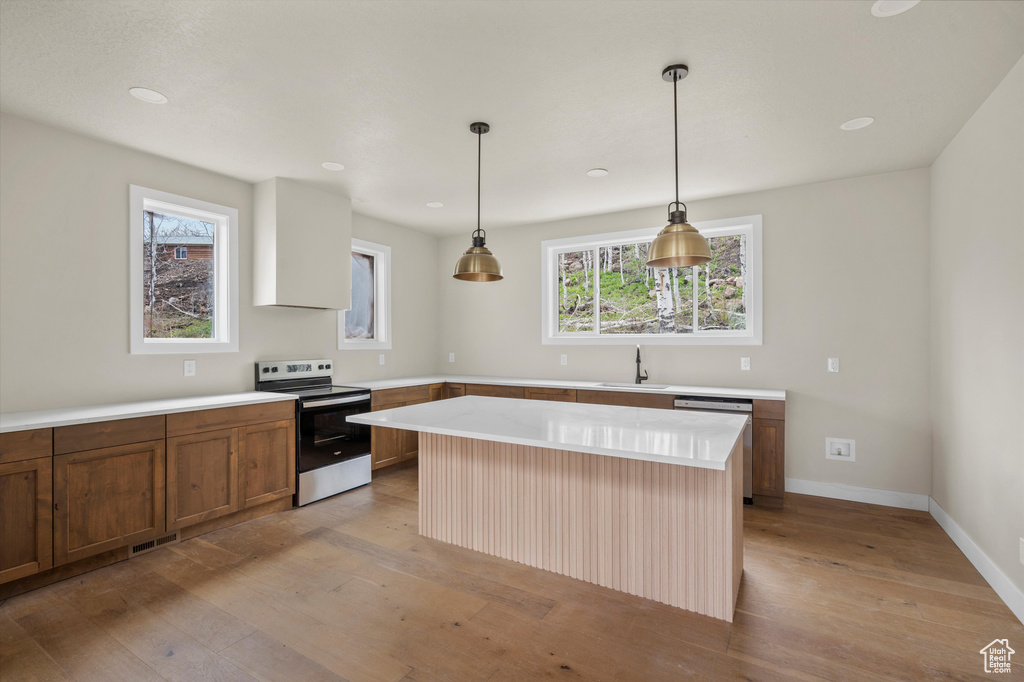 Kitchen featuring stainless steel appliances, a sink, light wood-style floors, and light countertops