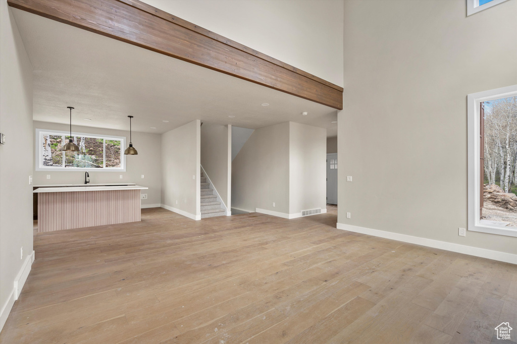 Unfurnished living room with light wood-style floors, baseboards, stairs, a sink, and recessed lighting