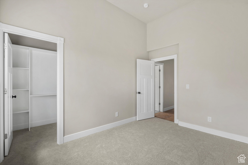 Unfurnished bedroom featuring carpet flooring, a spacious closet, baseboards, and a closet