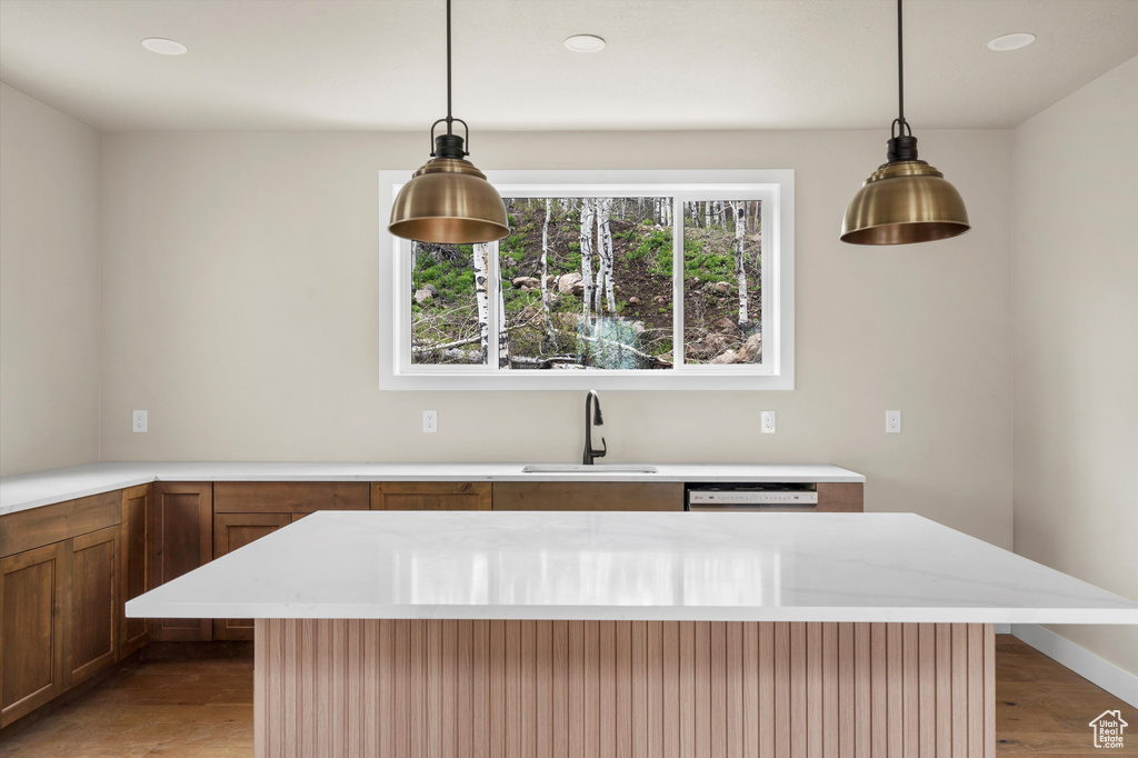 Kitchen with a sink, decorative light fixtures, light stone countertops, recessed lighting, and brown cabinetry