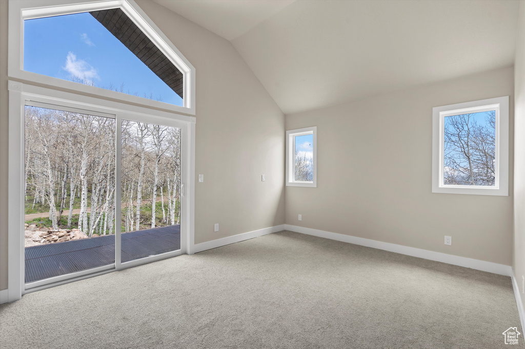 Carpeted empty room featuring lofted ceiling and baseboards