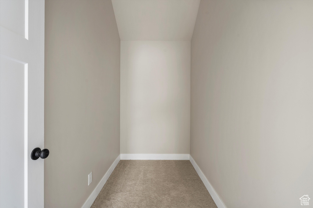 Empty room featuring carpet floors, baseboards, and vaulted ceiling
