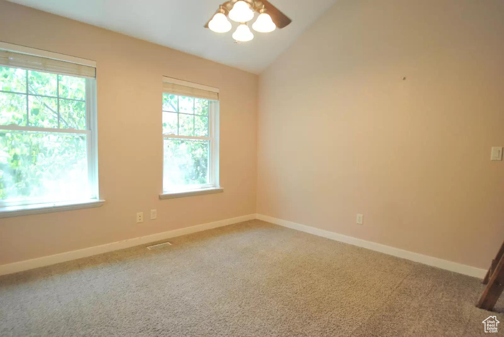 Spare room featuring carpet floors, ceiling fan, lofted ceiling, and baseboards