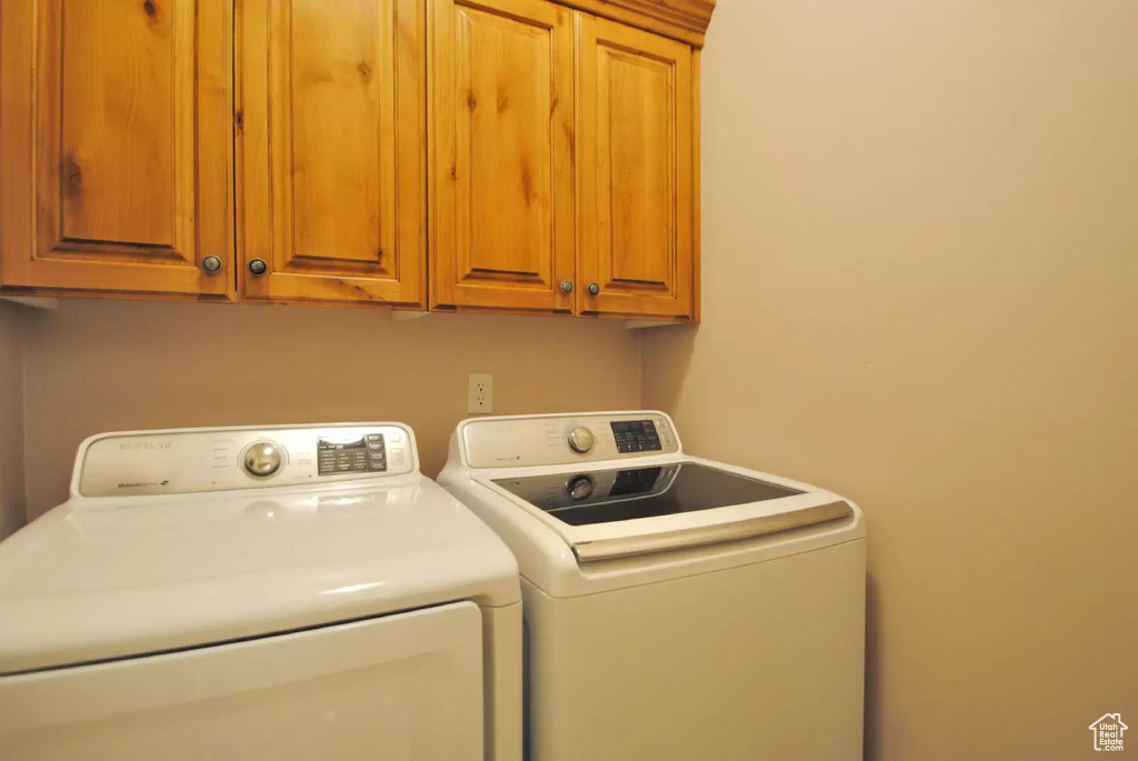 Washroom featuring separate washer and dryer and cabinet space