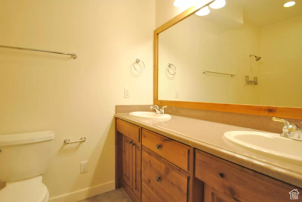 Full bath featuring double vanity, toilet, and baseboards