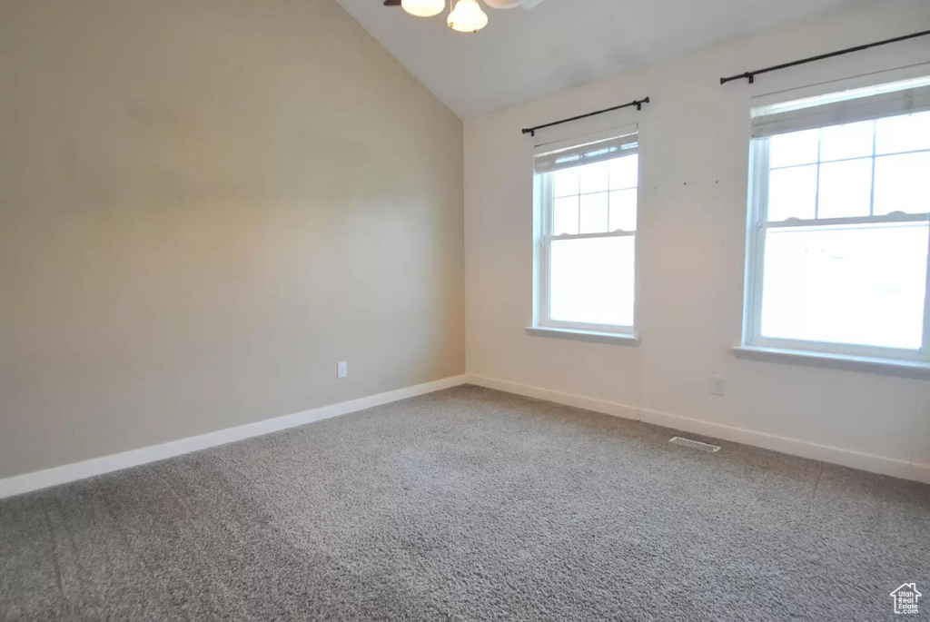 Carpeted spare room with plenty of natural light, vaulted ceiling, and baseboards