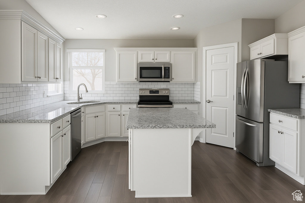 Kitchen featuring stainless steel appliances, a sink, a center island, white cabinets, and recessed lighting