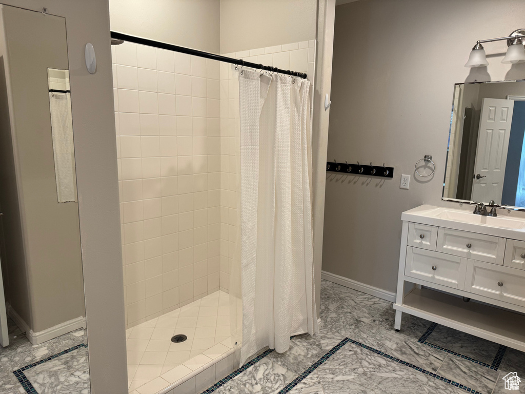 Full bath featuring a stall shower, vanity, and baseboards