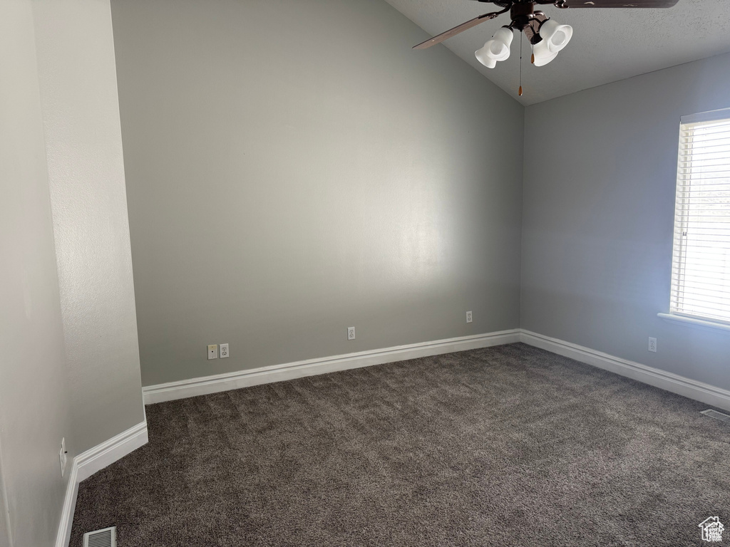 Unfurnished room with a ceiling fan, dark carpet, lofted ceiling, plenty of natural light, and baseboards